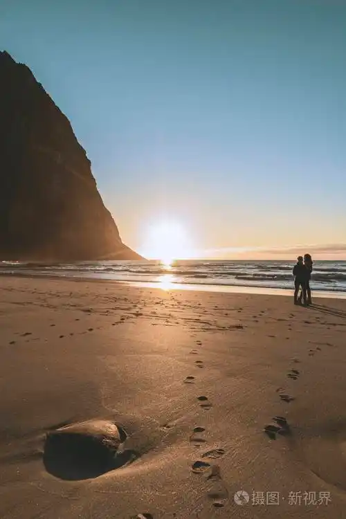 落日后的山上的海滩挪威一对情侣在海滩上拥抱